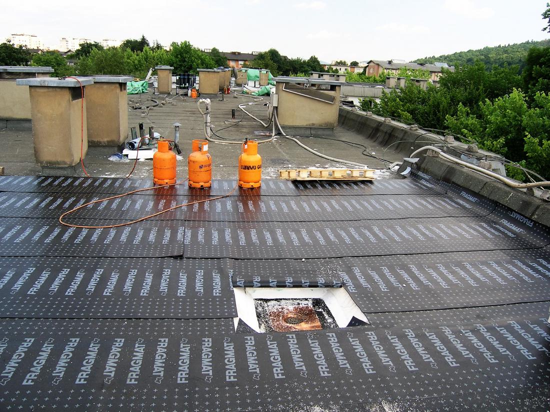 Sanacija ravne strehe na stanovanjskem bloku: vidijo se obstoječa hidroizolacija, nova toplotna izolacija in dvoslojna polimer-bitumenska hidroizolacija; sledijo še ekstrudirani polistiren, filc in prodec. Foto: arhiv GI ZRMK